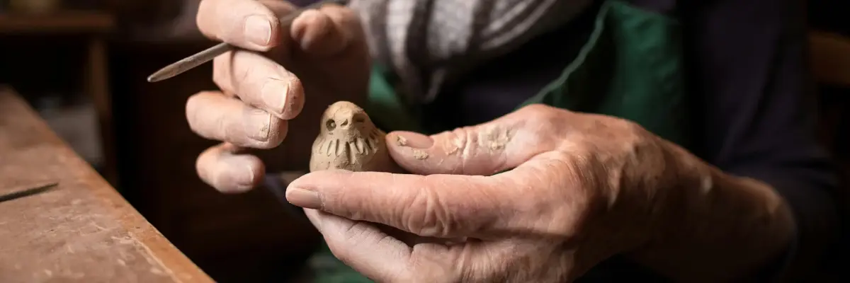 Old woman making clay figurine